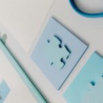A close-up of blue puzzle pieces placed neatly on an office desk with stationery.