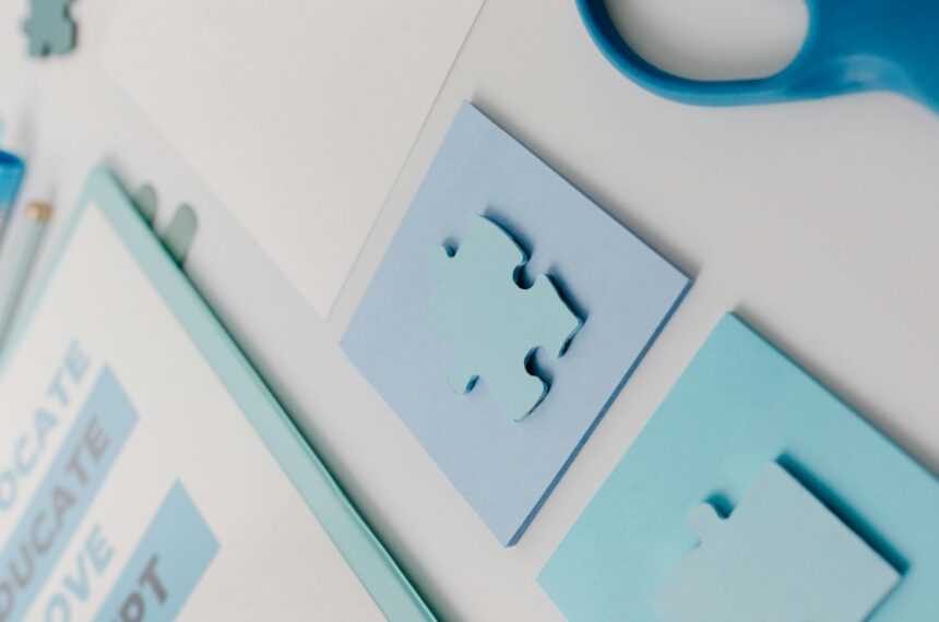 A close-up of blue puzzle pieces placed neatly on an office desk with stationery.