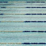 A tranquil view of an empty Olympic swimming pool with lane dividers.