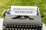 A vintage typewriter outdoors displaying a paper with the text 'Personalized Medicine'.