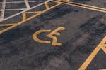Close-up view of an international accessibility symbol painted on a parking lot surface.