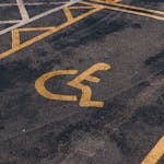 Close-up view of an international accessibility symbol painted on a parking lot surface.