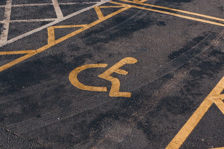 Close-up view of an international accessibility symbol painted on a parking lot surface.
