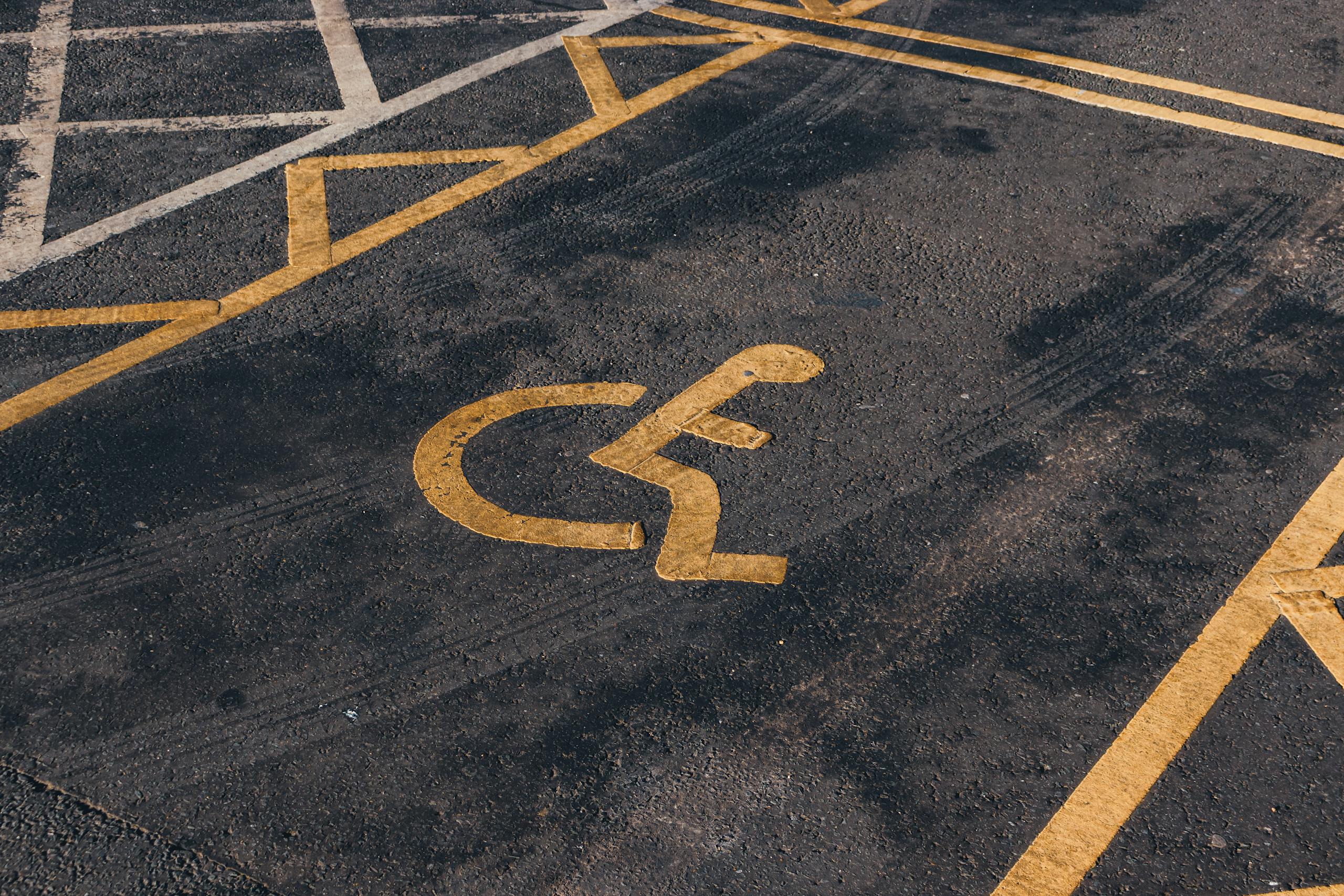 Close-up view of an international accessibility symbol painted on a parking lot surface.