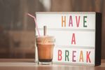 Iced coffee with straw beside illuminated light box saying 'Have a Break'.