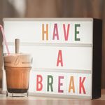 Iced coffee with straw beside illuminated light box saying 'Have a Break'.