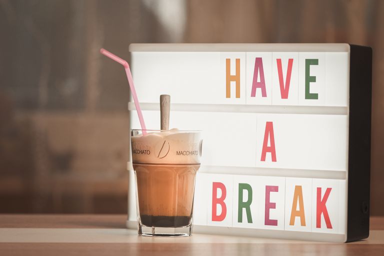 Iced coffee with straw beside illuminated light box saying 'Have a Break'.